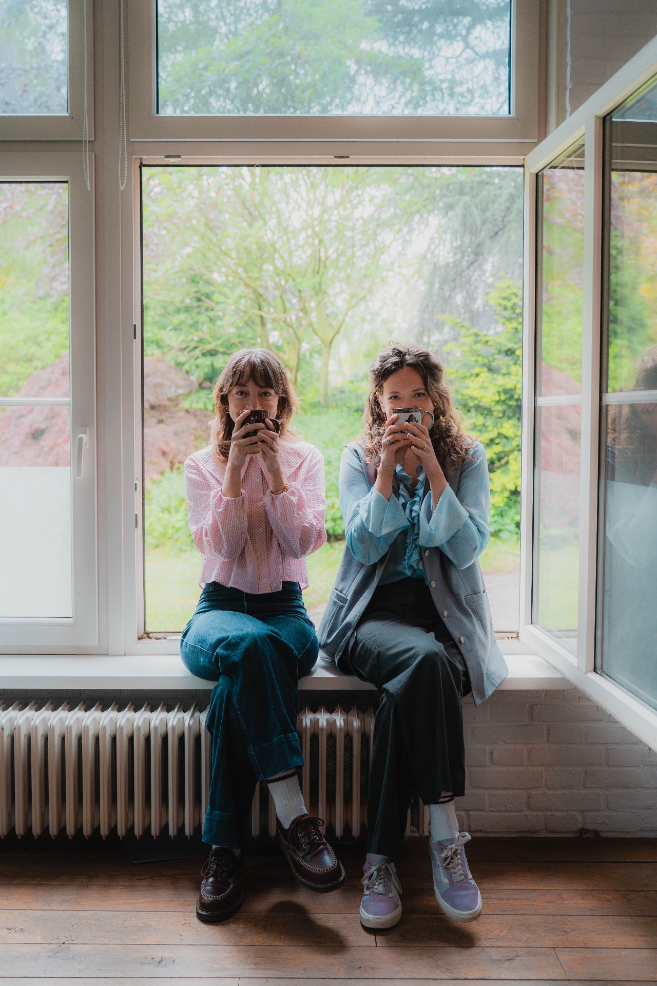 Evelien en Lisa samen bij het raam met een kopje thee